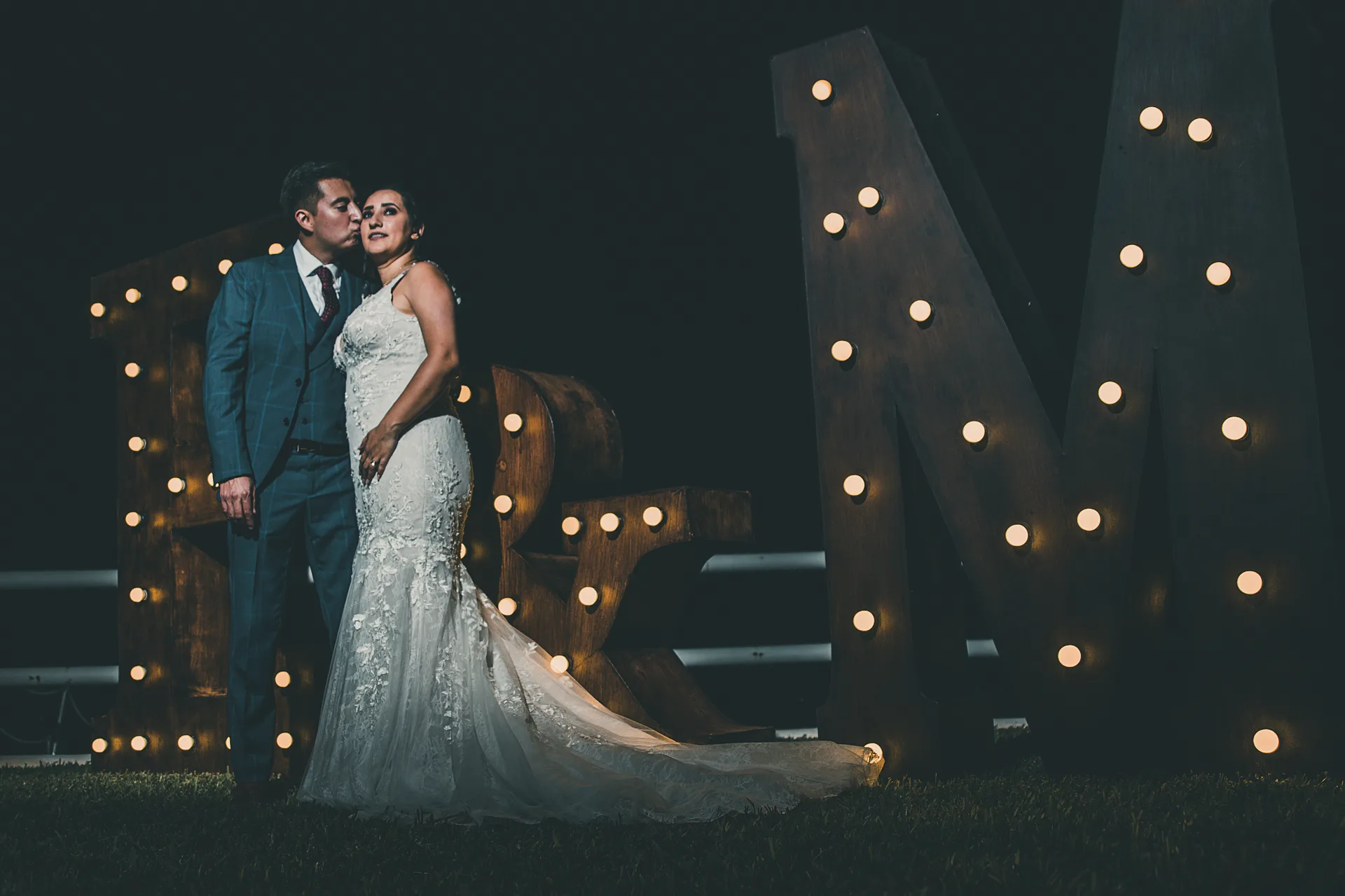 Novios frente a letras iluminadas durante la fiesta