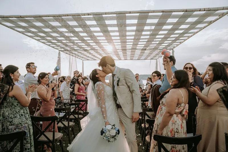 Beso de los novios rodeados por sus invitados