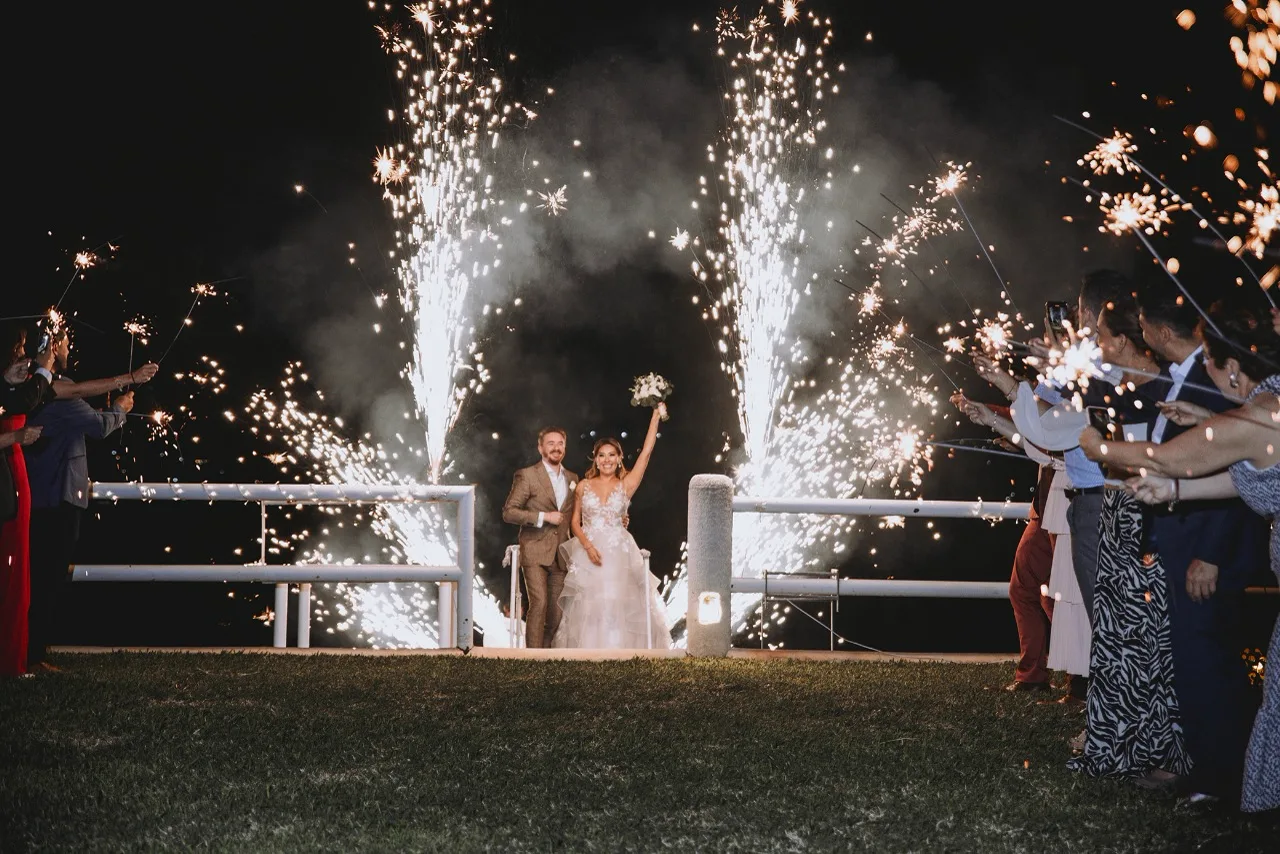 Salida de los novios entre fuentes de luces frías y los invitados